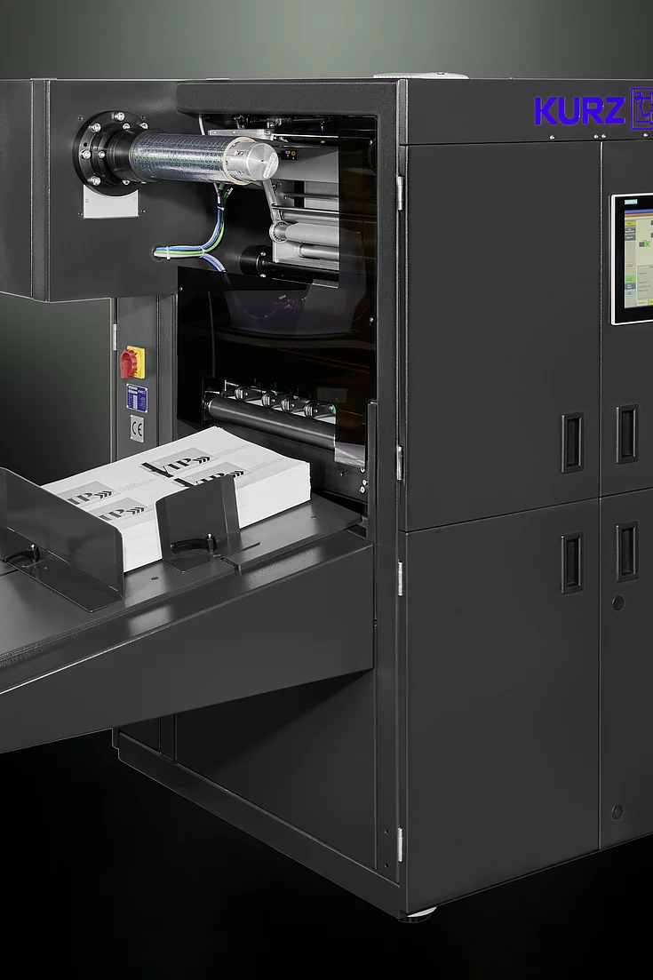 Digital Embellishment Solution from KURZ with open compartment, processing stacked printed sheets labeled "VIP".
