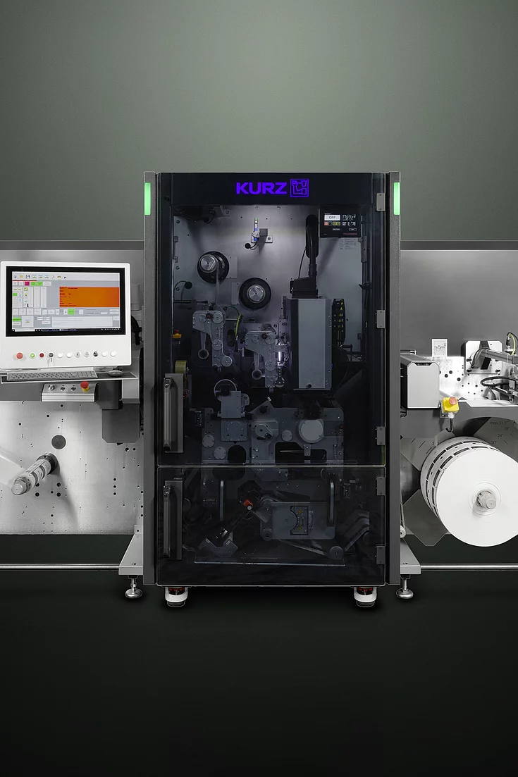 digital embellishment machine with control screens, labeled "KURZ" and "grafotronic," showing a roll of material.
